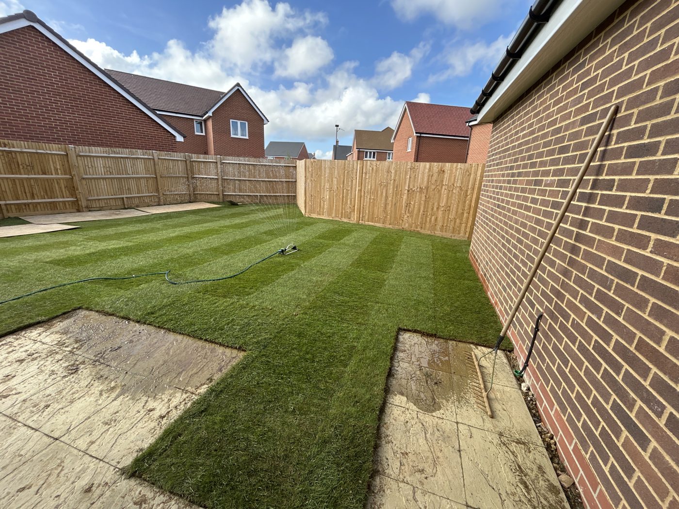 Watering — Turfing: a sprinkler watering in the new turf beside the patio.